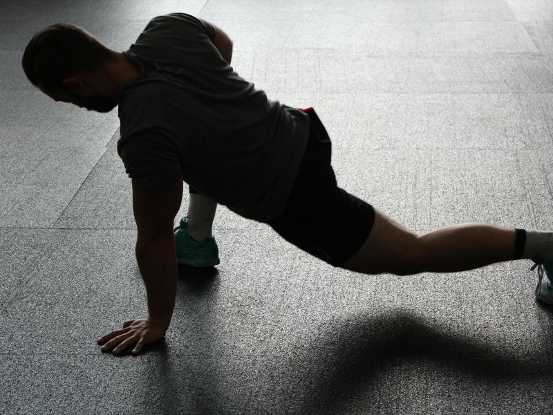 Athletic man in a plank position on a dark floor